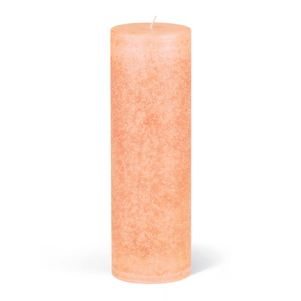 Une bougie cylindrique non allumée, de couleur pêche clair, repose sur un fond blanc et projette une petite ombre. La mèche dépasse au centre de la partie supérieure. La surface est légèrement mouchetée de façon irrégulière.