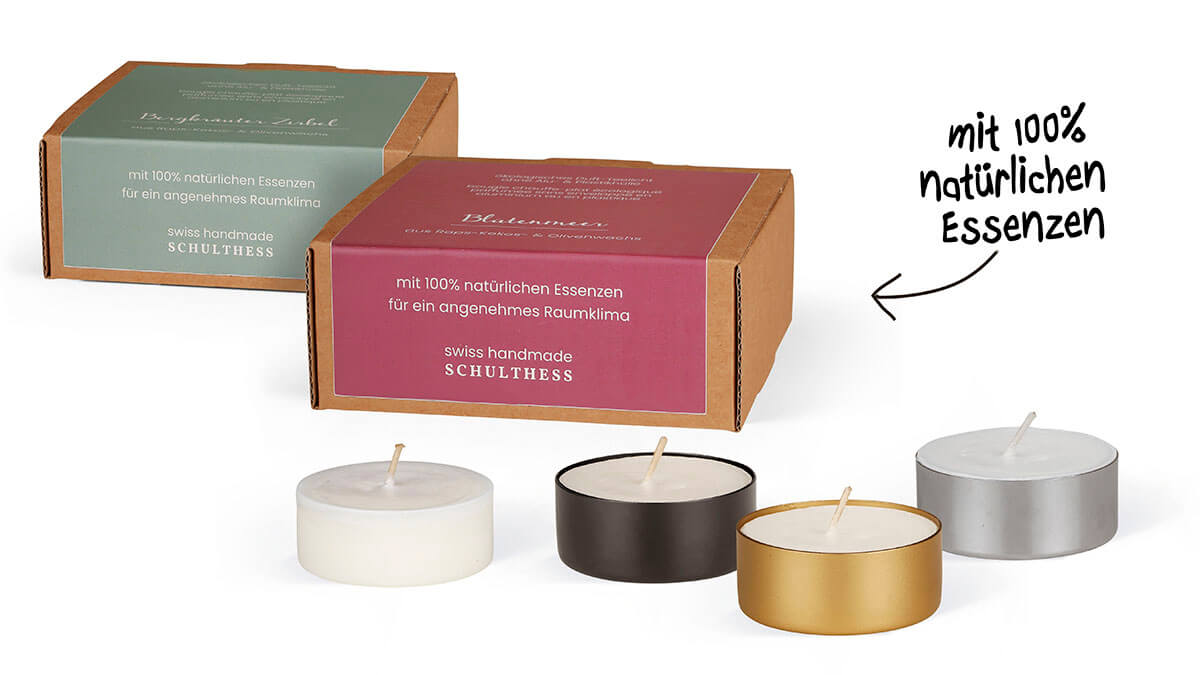 Zwei Duftkerzenpackungen stehen hinter vier Teelichtern. Die Etiketten sind hellgrün und weinrot. Teelichter in Weiß, Schwarz, Gold und Silber. Aufschrift: "100% natürliche Essenzen". Pfeil nach links.