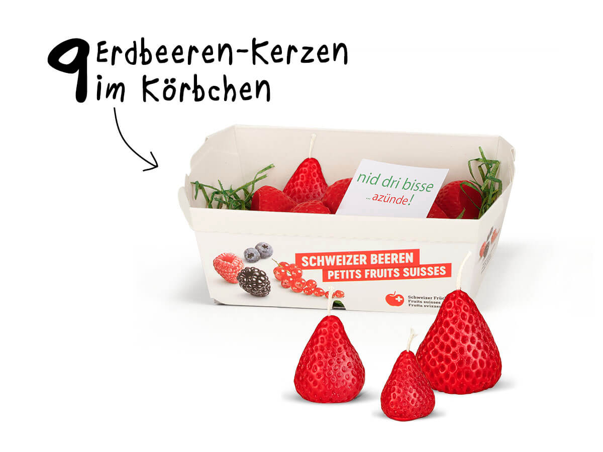 On a white background are strawberry candles in a white paper basket with ‘Schweizer Beeren’ and ‘Petits Fruits Suisses’. A note inside reads ‘nid dri bisse ...azünde!’. In front are three more strawberry candles.