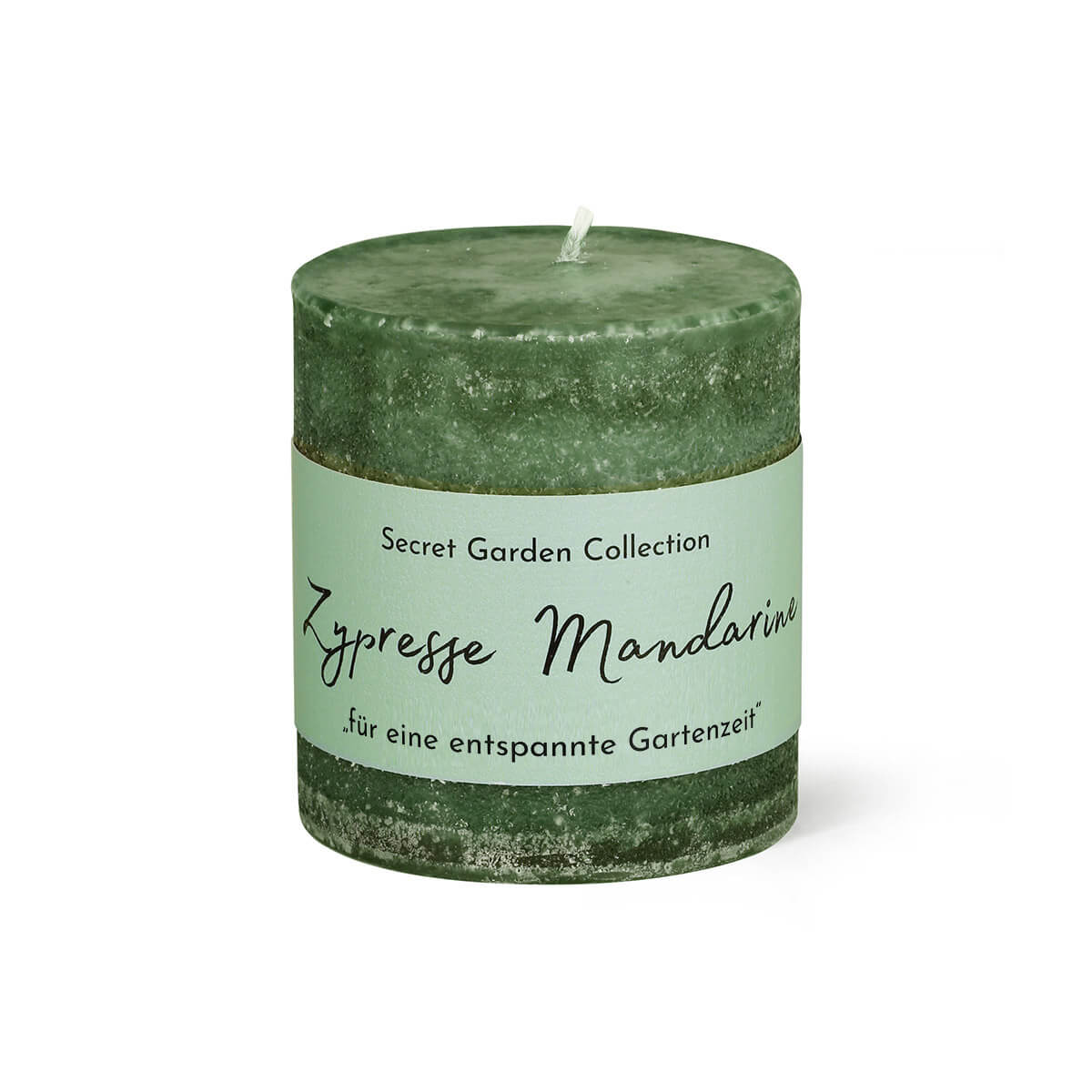 Candela profumata cilindrica, di colore verde scuro, con texture ruvida. Etichetta verde chiaro al centro: "Secret Garden Collection", "Cipresso e mandarino" e "per un momento di relax in giardino". Stoppino bianco visibile nella parte superiore.